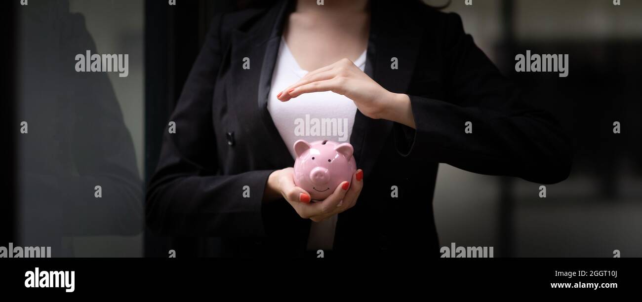 Bannerbild, Business Woman Hand hält und Abdeckung Sparschwein. Sparen Sie Geld und finanzielles Investitionskonzept Stockfoto