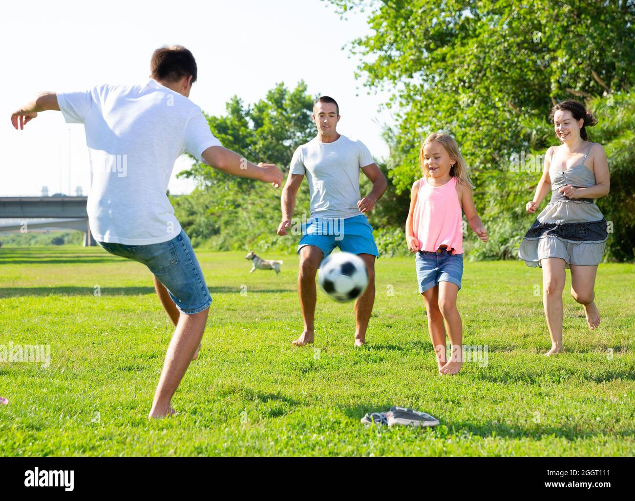 Gruppe von lachenden Kindern und Eltern Spaß zusammen draußen Fußball spielen Stockfoto