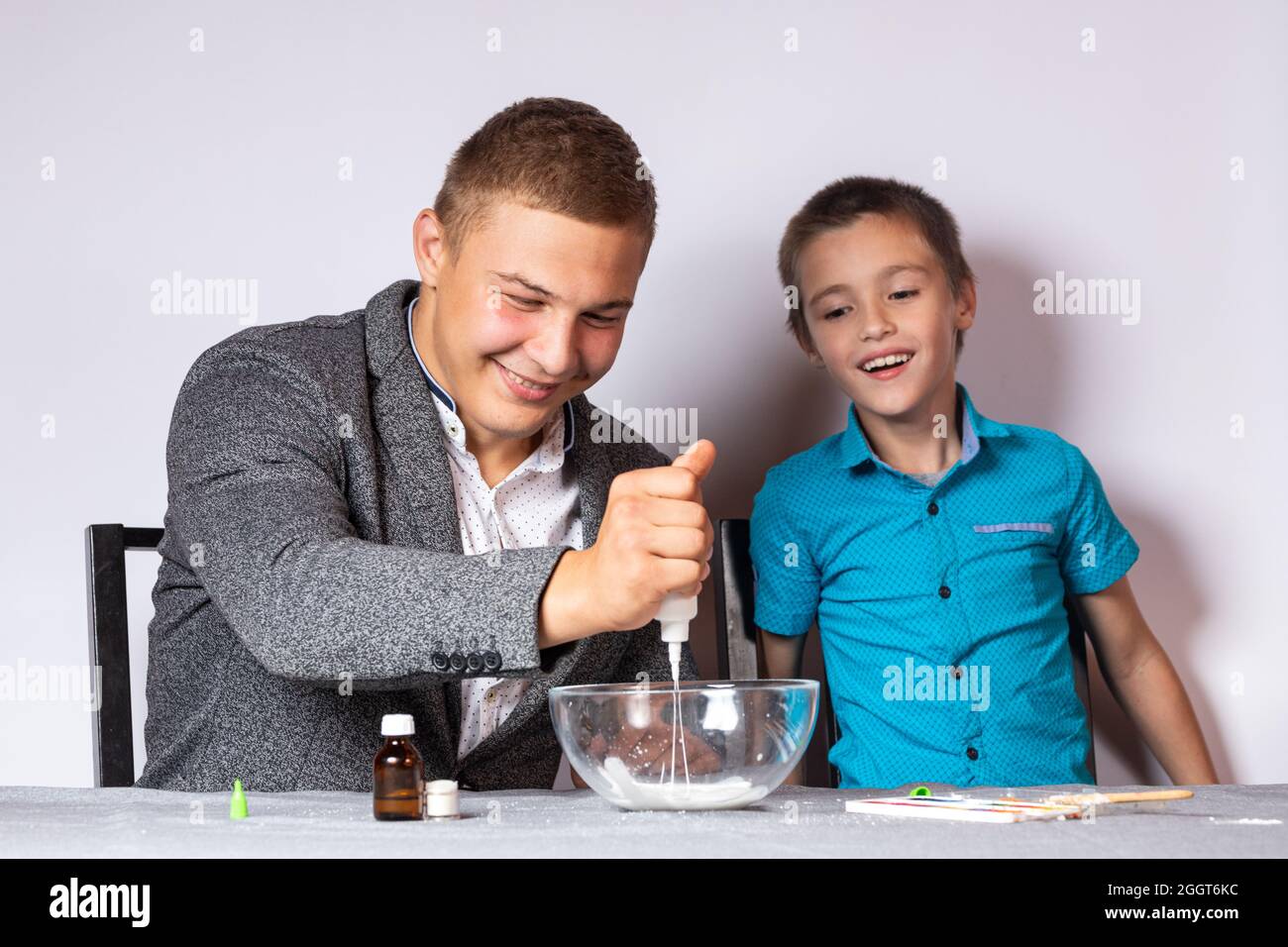 Konzept der chemischen aus- und Weiterbildung. Nahaufnahme eines Jungen und seines Vaters, die ein heimisches Experiment machten, Schleim aus Klebstoff, Natriumtetraborat A machten Stockfoto