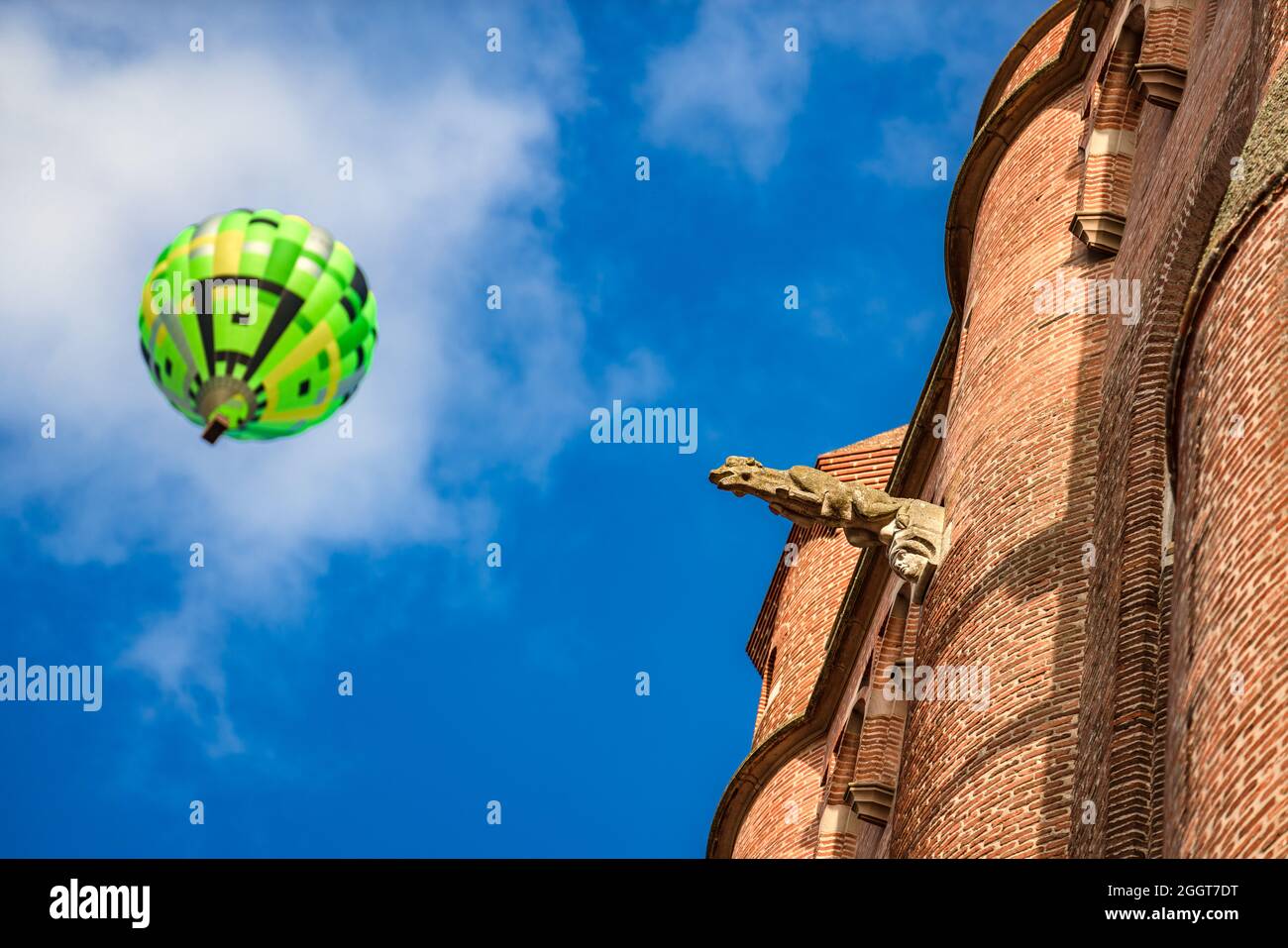Albi, Frankreich. 8. August 2021. Detail der Albi Kathedrale Fassade. Im Hintergrund fliegt ein verschwommener Heißluftballon über die Stadt. Stockfoto