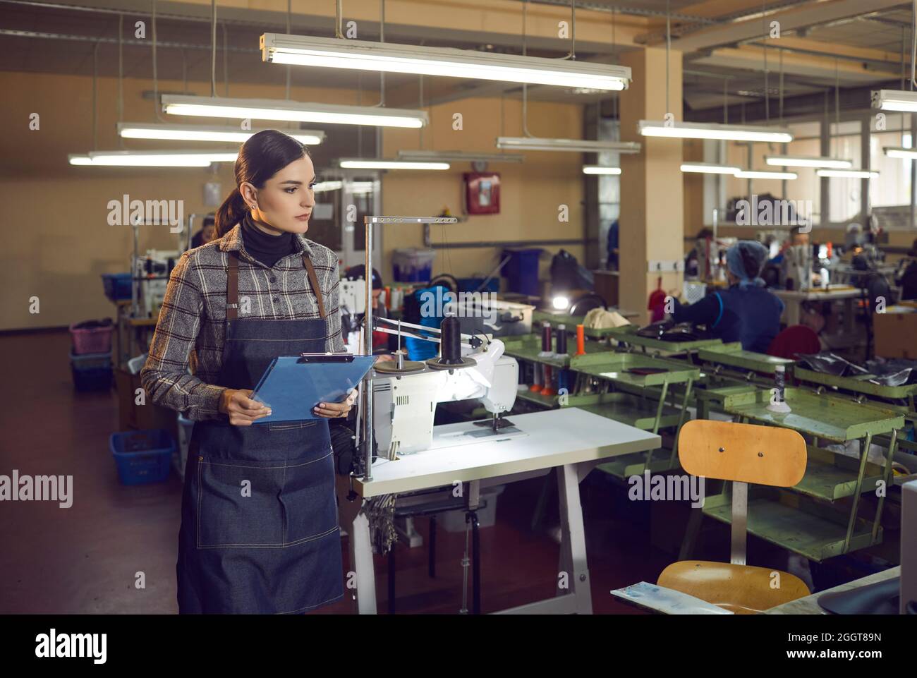 Ernsthafter Arbeiter, der in einer großen Nähwerkstatt in der Schuhfabrik steht Stockfoto
