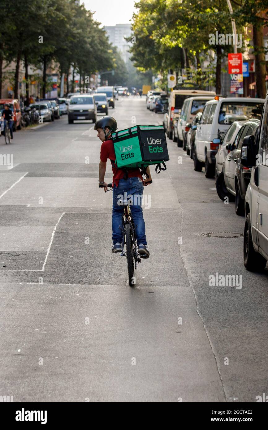 Berlin, Deutschland. September 2021. Silvan, ein Fahrer für den Food Delivery Service Uber Eats, fährt auf einer Straße im Berliner Bezirk Friedrichshain mit einem Transportkoffer auf dem Rücken ein Fahrrad. Quelle: Carsten Koall/dpa/Alamy Live News Stockfoto