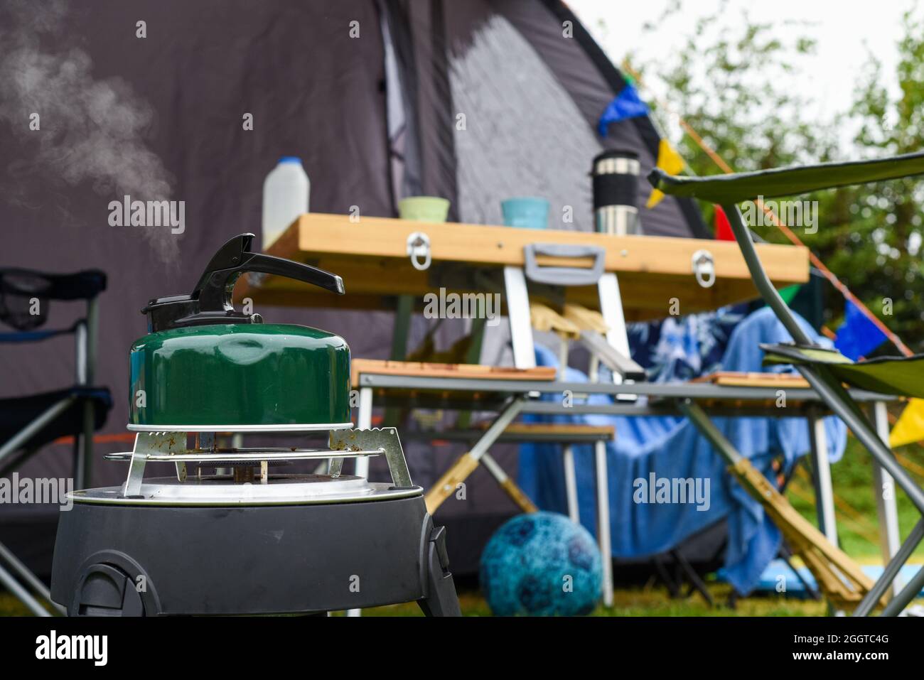 Am Morgen einen Wasserkocher vor einem Zelt auf einem Campingplatz kochen Stockfoto