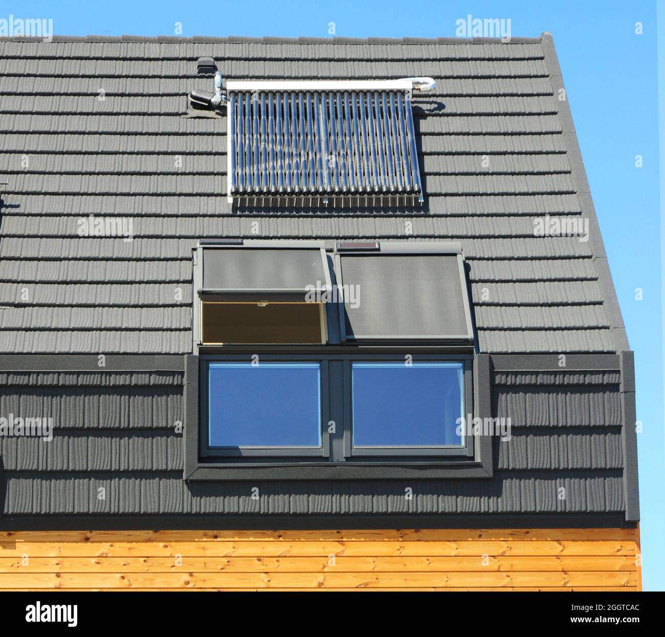 Modernes Hausdach mit Dachhimmel, Sonnenkollektoren und Solar-Warmwasserbereiter (SWH)-System für Energieeinsparung und Energieeffizienz. Fensterläden und S Stockfoto
