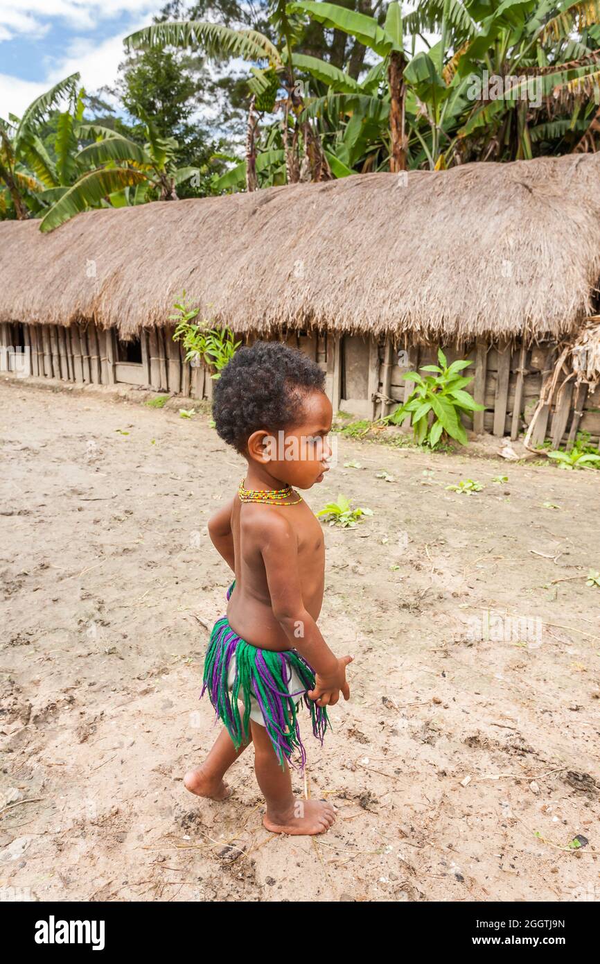 Wamena, Indonesien - 9. Januar 2010: Kind des Dani-Stammes steht in nea Strohhäusern, Papua-Neuguinea. Stockfoto