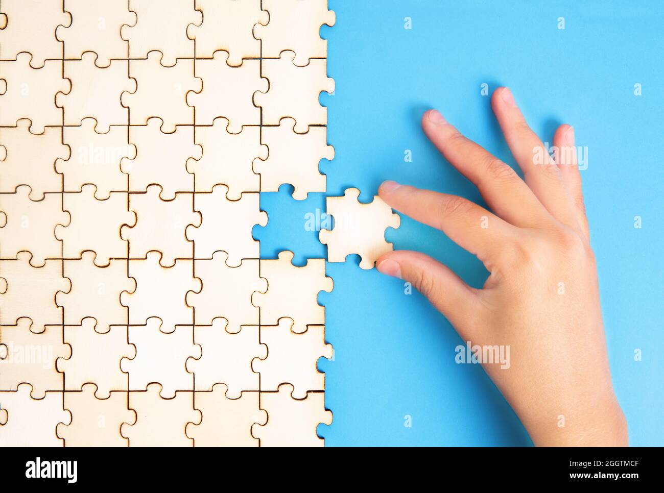 Weibliche Hand, die das letzte Puzzleteil in Position setzt. Abschlusskonzept. Stockfoto