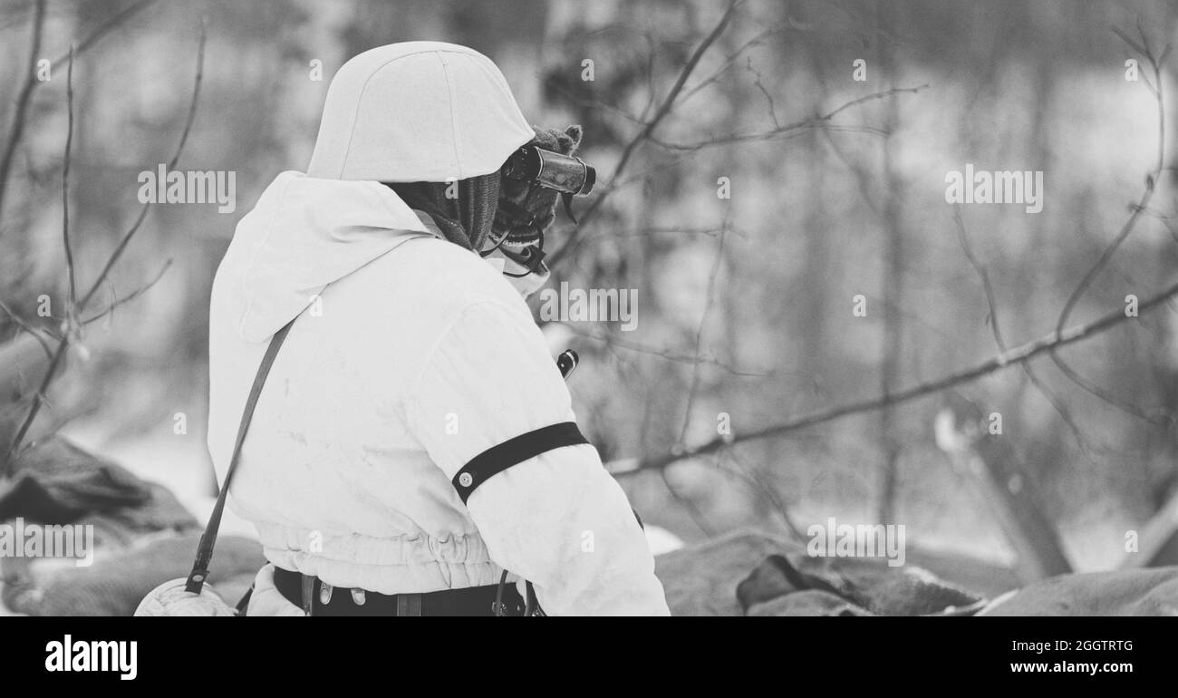 Wehrmachts-Infanterie-Soldat im Zweiten Weltkrieg Soldaten sitzen im Hinterhalt im Winterwald und schauen auf das Fernglas der Alten Armee. Historische Re Stockfoto