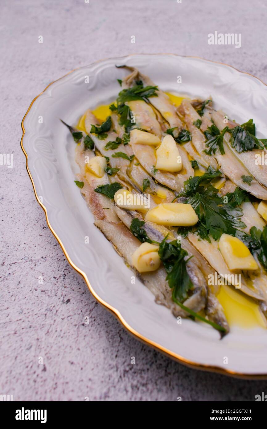 Marinierte Sardellen in Essig und Olivenöl mit Petersilie und Knoblauch. Stockfoto