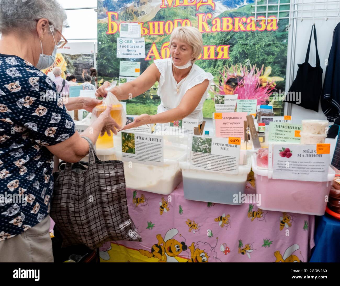 Eine Frau, die Honig an eine Kundin am Stand, auf der orthodoxen Messe, Sokolniki, Moskau, Russland verkauft Stockfoto