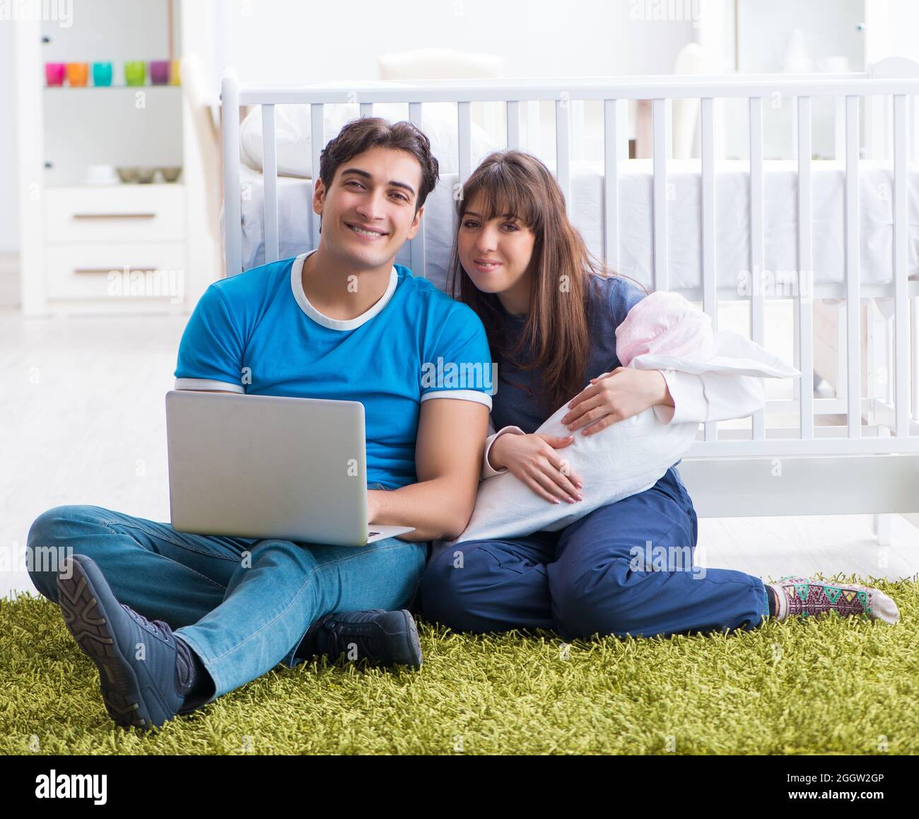 Die jungen Eltern mit ihren neugeborenen Babys sitzen auf dem Teppich Stockfoto