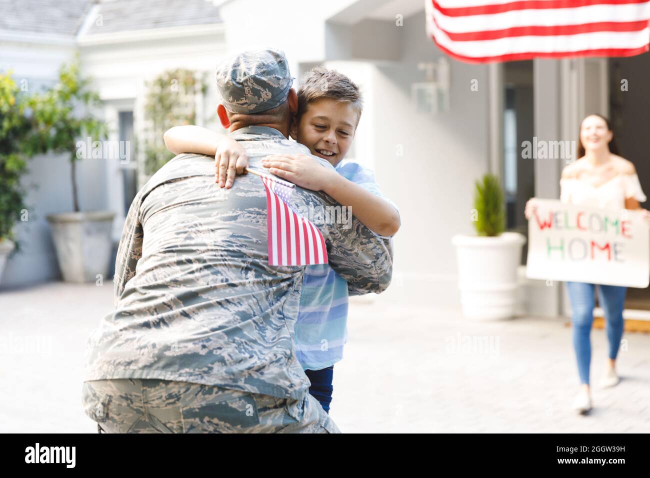 Kaukasischer männlicher Soldat mit Sohn und Frau vor dem Haus, das mit amerikanischer Flagge geschmückt ist Stockfoto