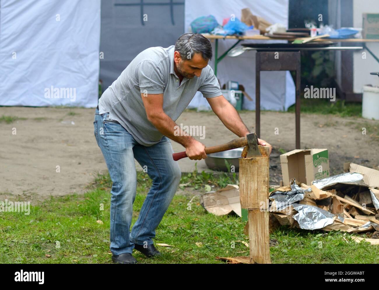 Mann hackt einige Holzspäne mit einer Axt für einen beweglichen Holzofen. Feier des Ramadan, Bruch des Fastens. 19.Mai 2018. Kiew, Ukraine Stockfoto