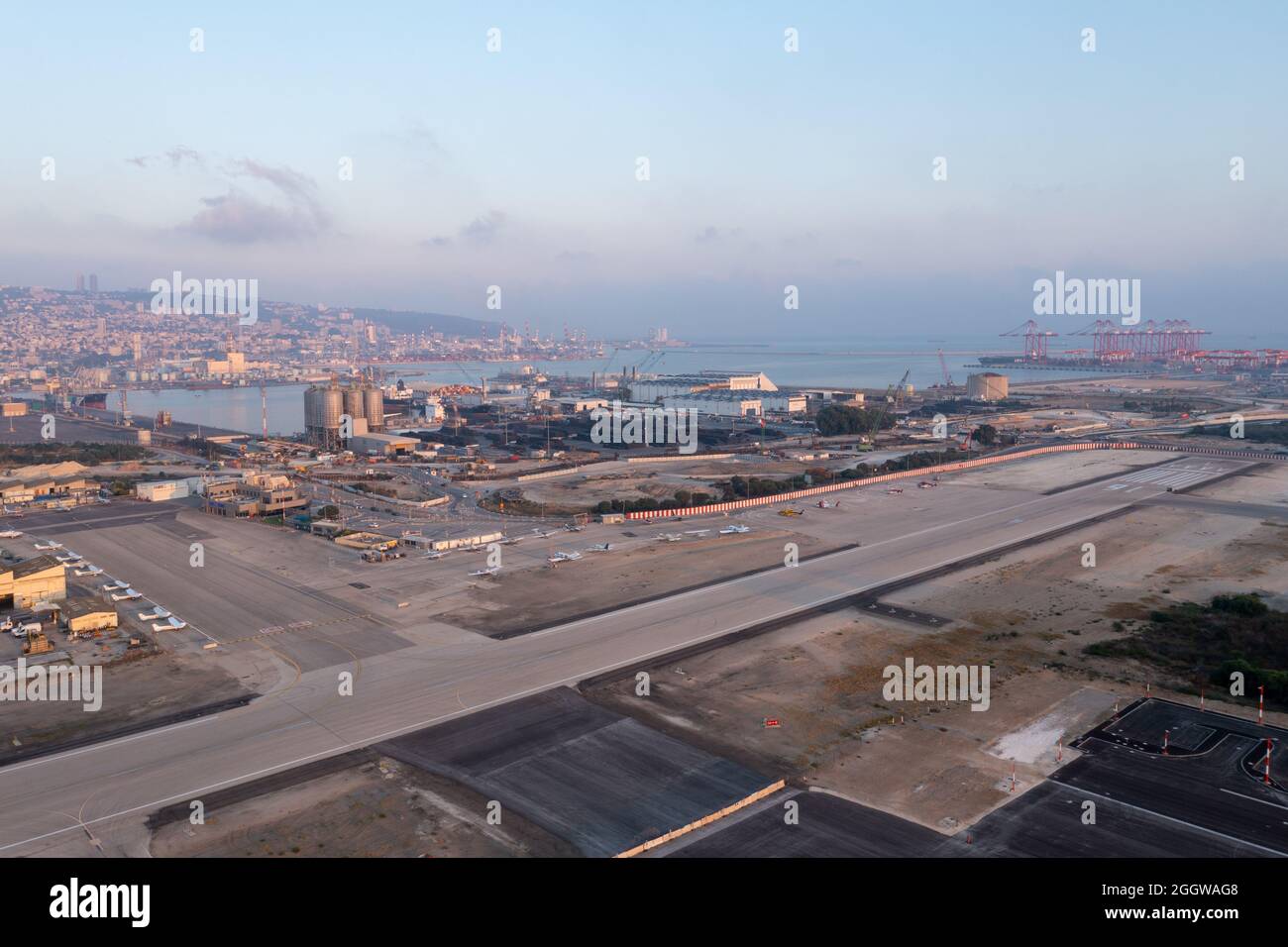 Haifa Flughafen und Start- und Landebahn mit der Skyline der Stadt im Hintergrund, Luftaufnahme. Stockfoto