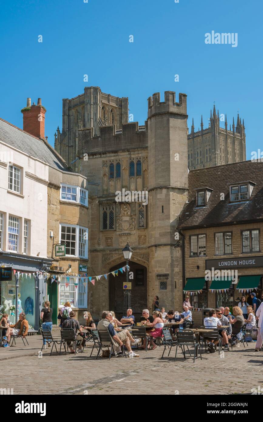 Wells Somerset, Blick im Sommer auf Menschen, die an Cafeterien im historischen Market Place im Zentrum von Wells, Somerset, England, Großbritannien, sitzen. Stockfoto