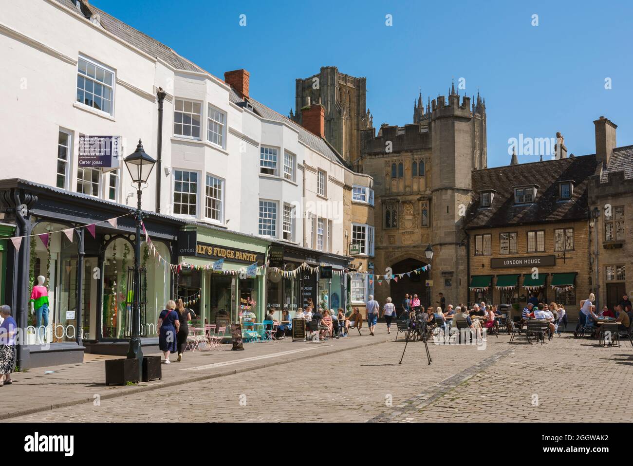 Wells Market Place, Blick im Sommer auf den Market Place mit dem mittelalterlichen Bishop's Eye Torhaus, das zur Wells Cathedral, Somerset, England, Großbritannien führt Stockfoto