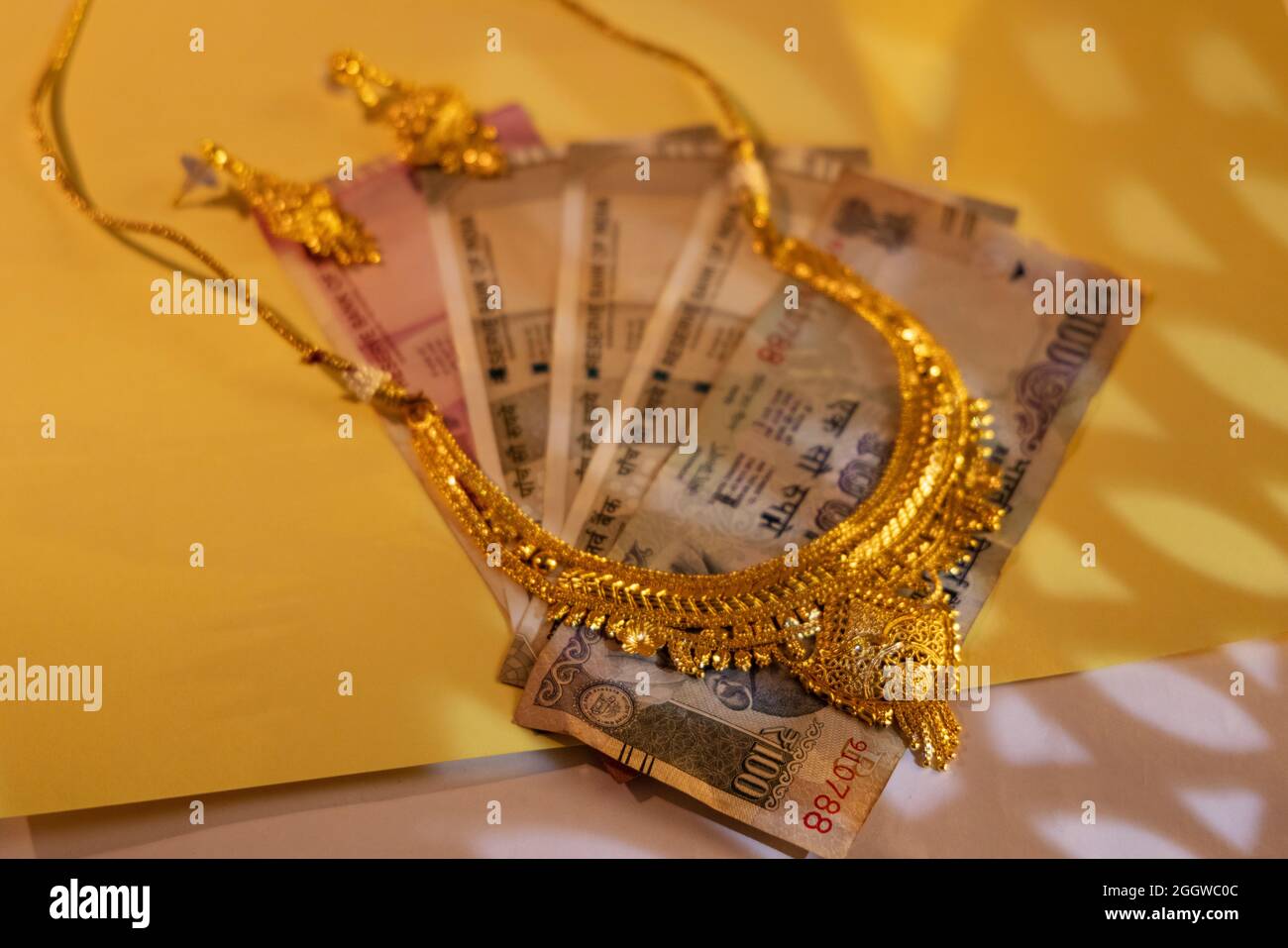 Goldene Juwelen auf indischen Geldscheinen. Stockfoto