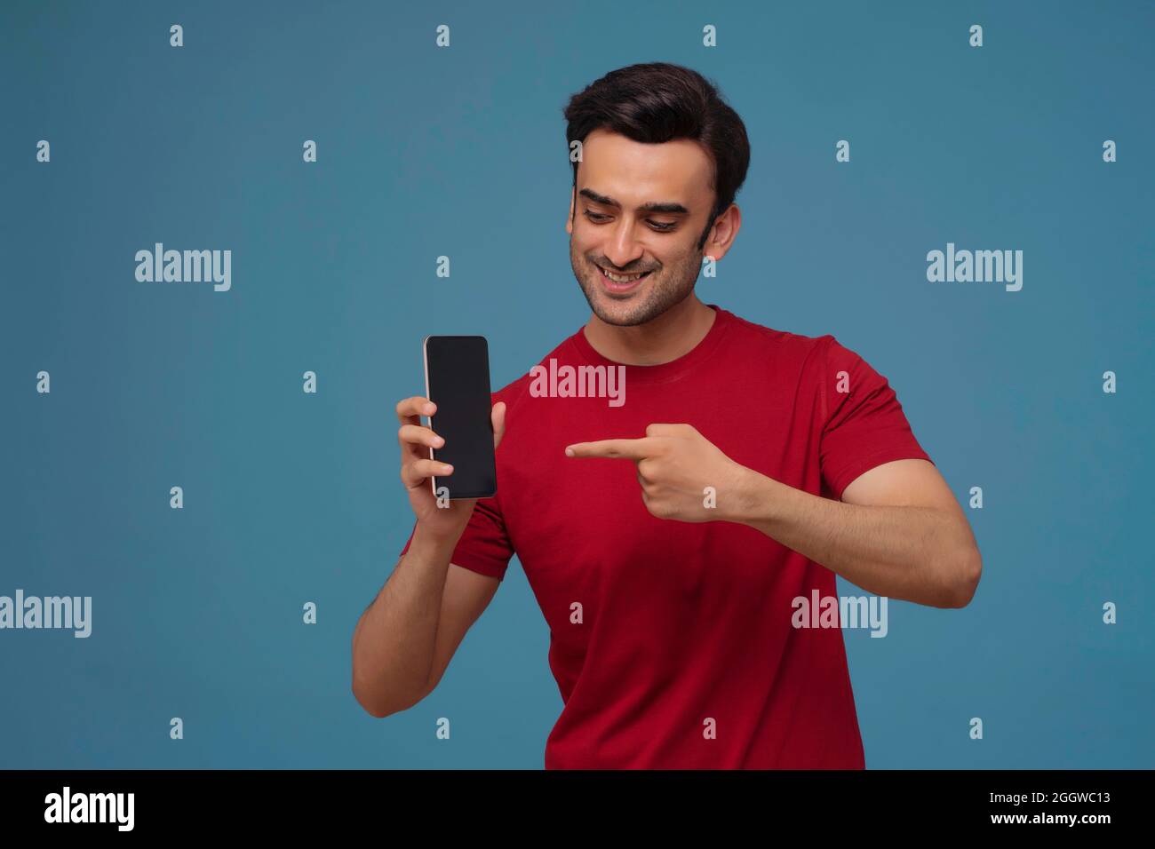 Porträt eines jungen Mannes mit Handy in der Hand vor schlichtem Hintergrund. Stockfoto