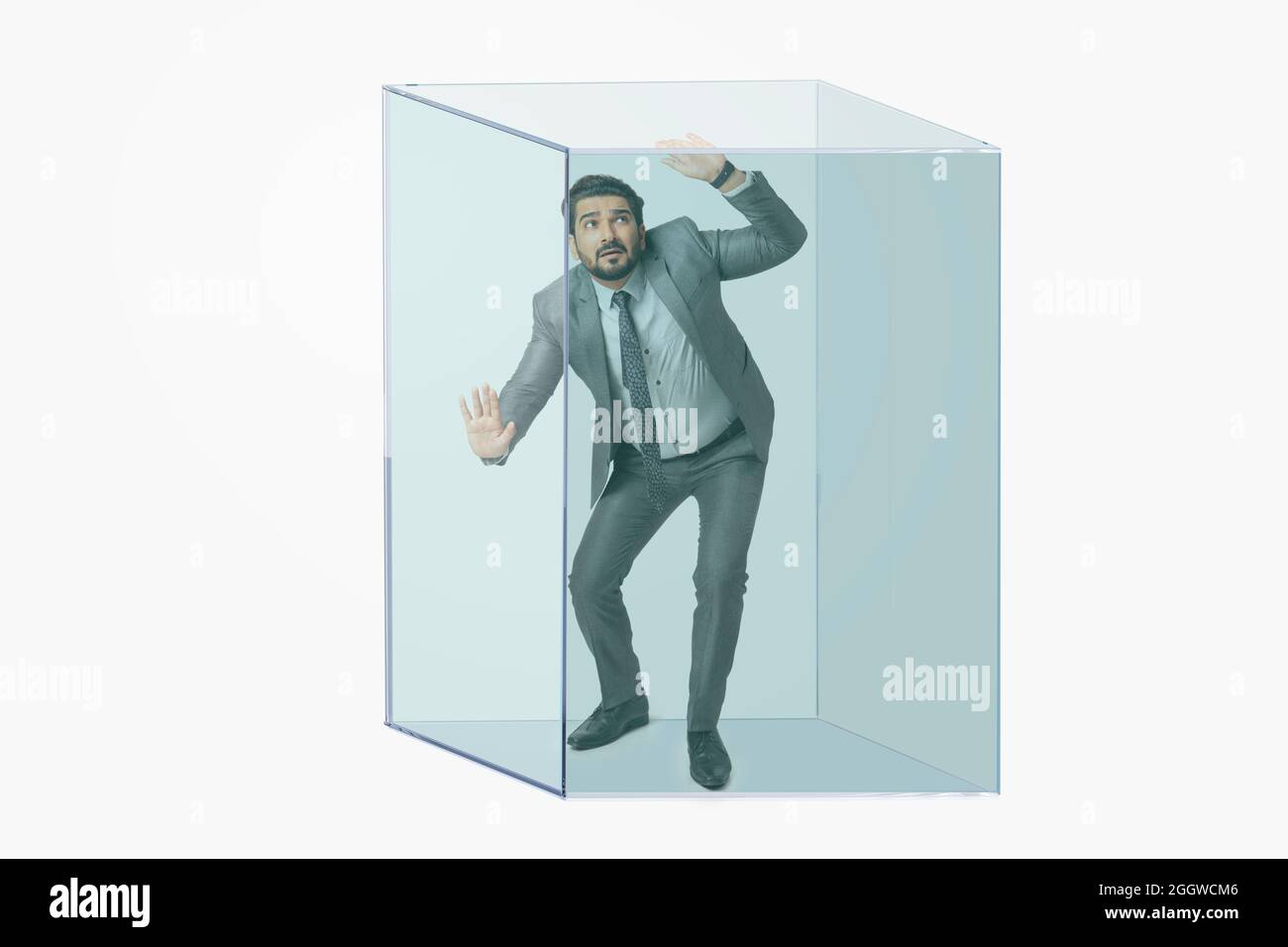 Porträt eines Mannes in formellem Business-Anzug in einem transparenten Würfel gefangen. Stockfoto
