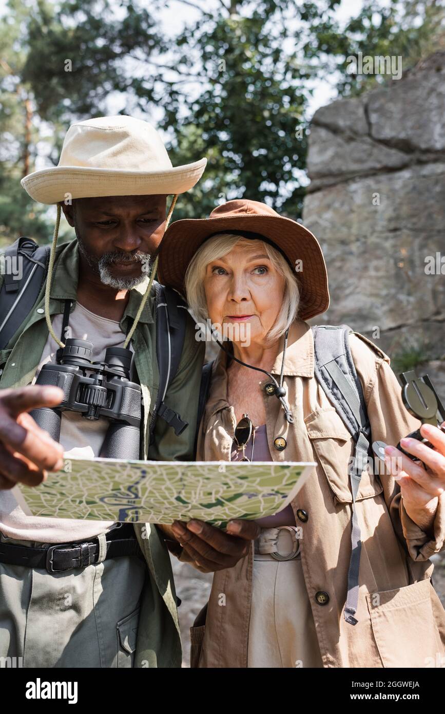 Ältere multiethnische Wanderer mit Kompass und Karte stehen im Wald Stockfoto