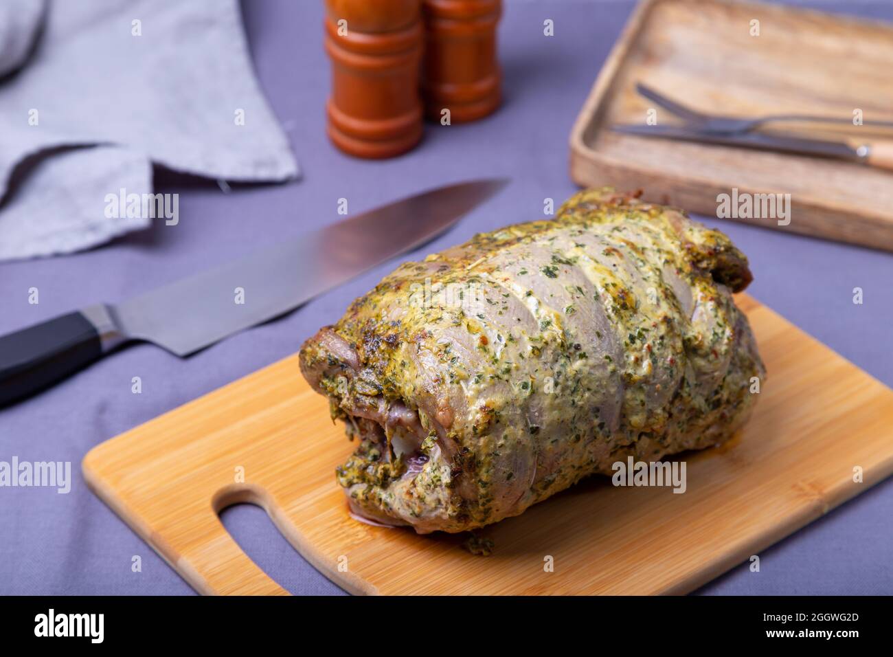 Putenschenkel auf dem Knochen, gebacken mit Senf, Petersilie, Gewürzen und Chili auf einem Holzbrett. Nahaufnahme. Stockfoto