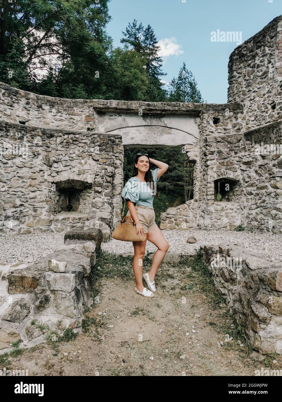 Porträt einer stilvollen jungen tausendjährigen Frau, die vor einer mittelalterlichen Ruine steht. Stockfoto