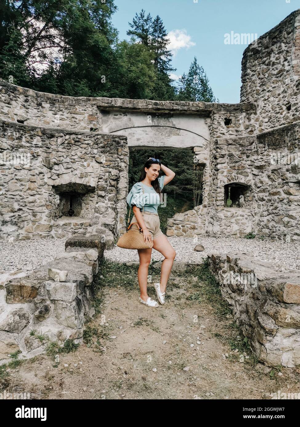 Porträt einer stilvollen jungen tausendjährigen Frau, die vor einer mittelalterlichen Ruine steht. Stockfoto