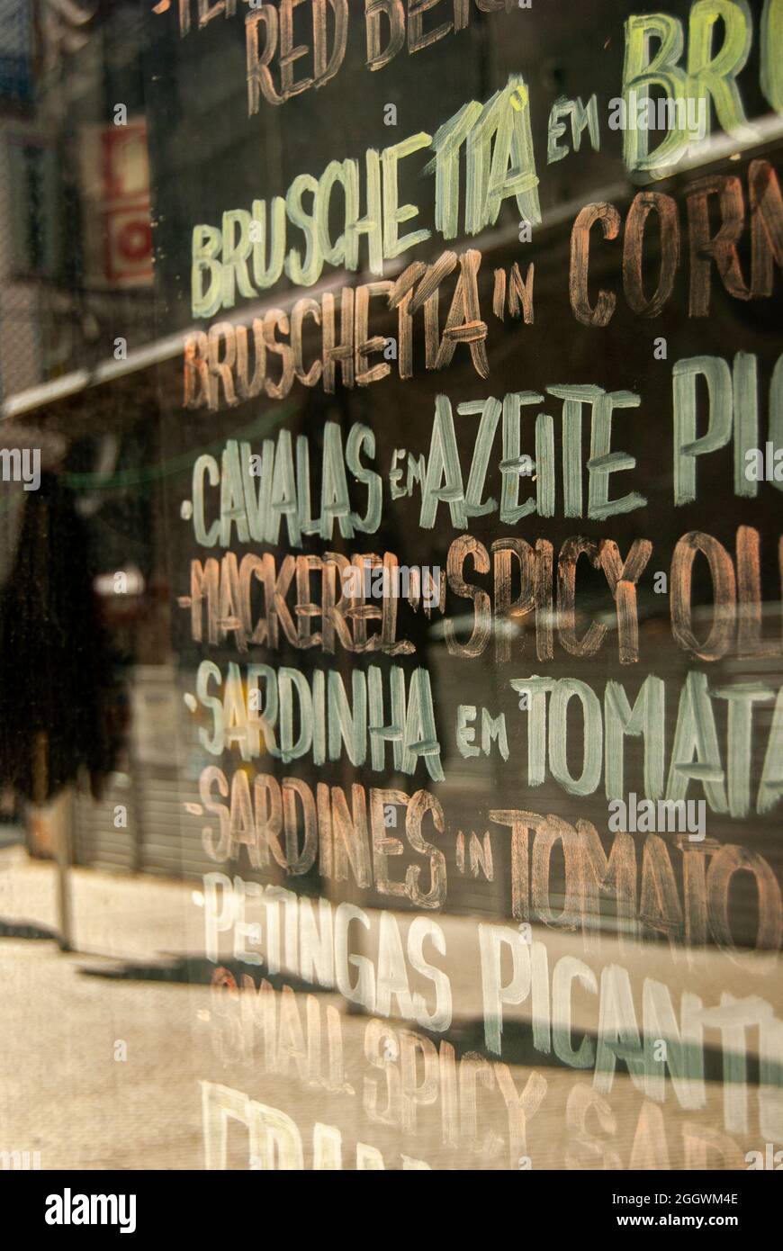 Ein Fenster des portugiesischen Café-Restaurants mit Namen traditioneller Gerichte in portugiesischer und englischer Sprache - Vertikal, selektiver Fokus Stockfoto