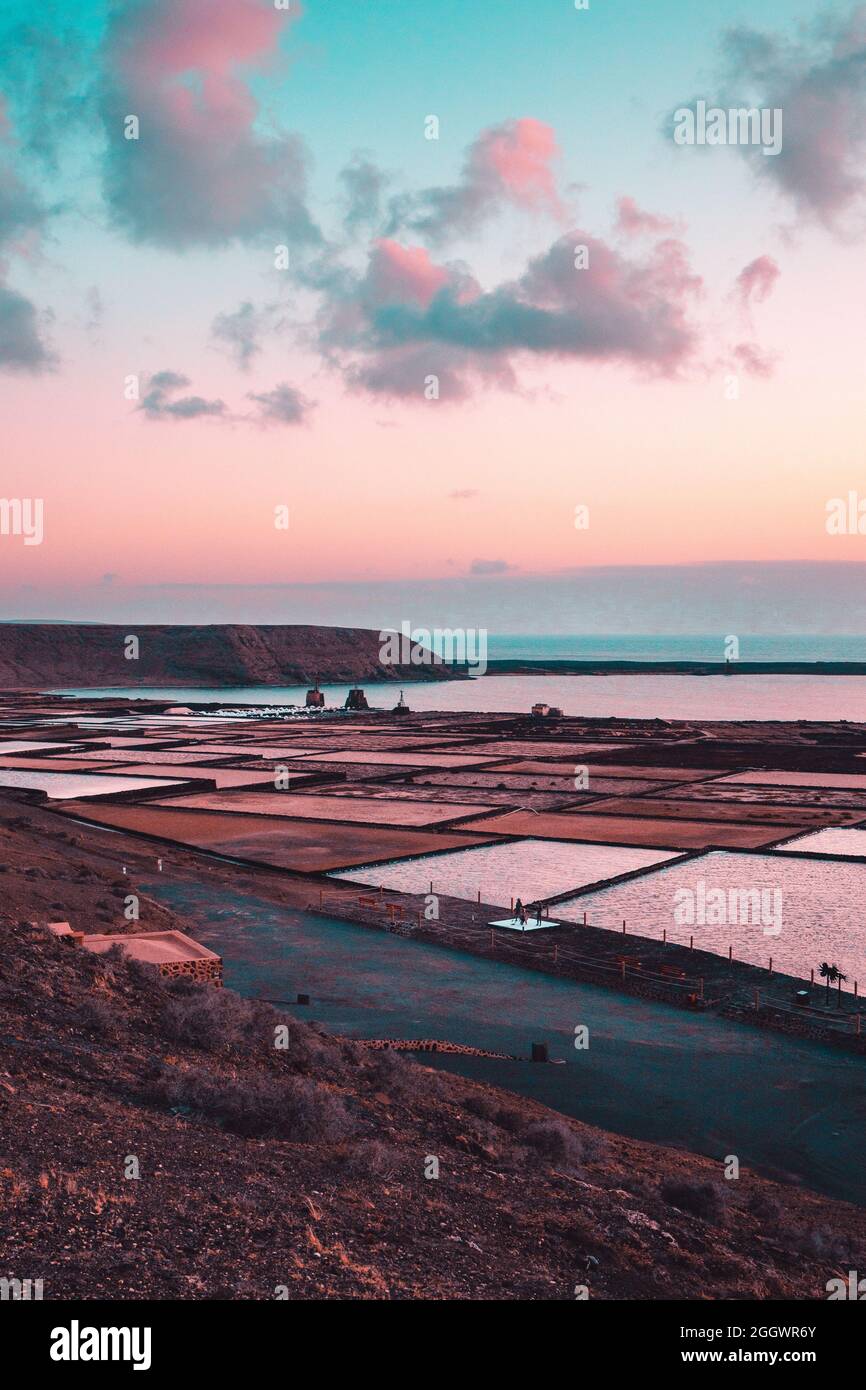 Vertikale Aufnahme von natürlichen Salzverdampfungsteichen bei Sonnenuntergang Stockfoto