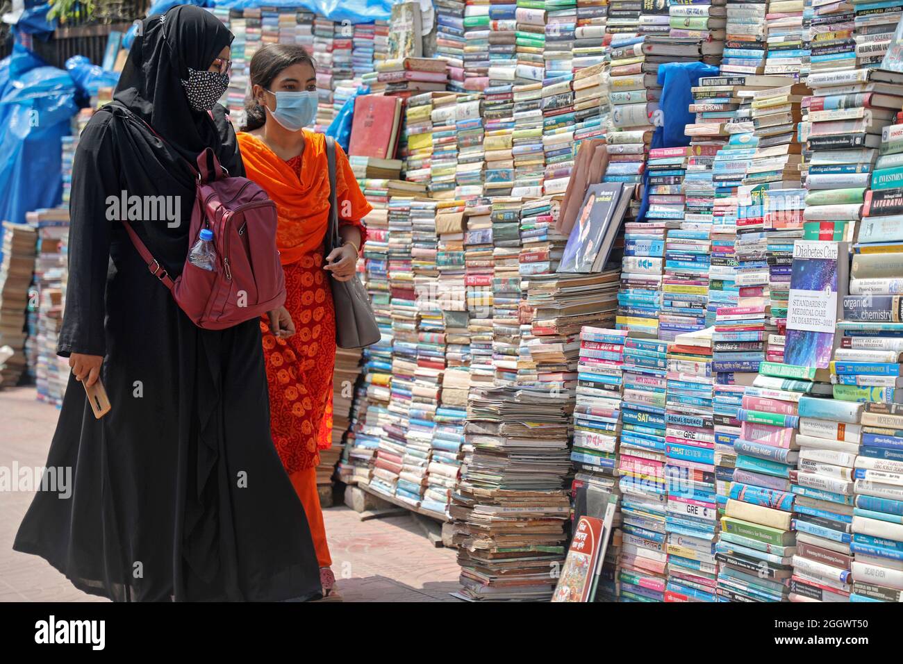 Dhaka, Bangladesch. September 2021. Zwei Frauen gehen vor einen Haufen Bücher, die aufgrund der Schließung von Buchhandlungen aufgrund der mangelnden Verkäufe aufgrund der Covid-19-Situation zu sehr niedrigen Preisen auf dem externen Markt versteigert wurden. Die alten Buchhandlungen in der Hauptstadt Newmarket haben aufgrund der Schließung von Bildungseinrichtungen aufgrund der Prävalenz von Covid-19 lange Zeit Verluste erlitten. Am 3. September 2021 in Dhaka, Bangladesch. Kredit: Eyepix Gruppe/Alamy Live Nachrichten Gutschrift: Eyepix Gruppe/Alamy Live Nachrichten Stockfoto