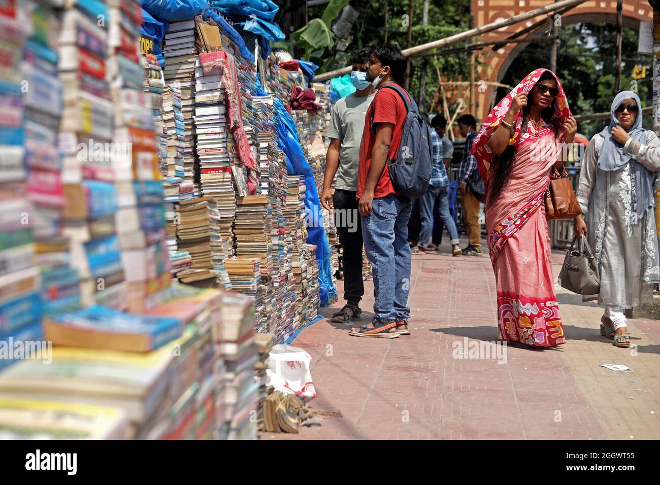 Dhaka, Bangladesch. September 2021. Ein Mann sieht aus, wie viele Bücher aufgestapelt wurden, die aufgrund der Schließung von Buchhandlungen aufgrund mangelnder Verkäufe aufgrund der Covid-19-Situation zu sehr niedrigen Preisen auf dem externen Markt versteigert wurden. Die alten Buchhandlungen in der Hauptstadt Newmarket haben aufgrund der Schließung von Bildungseinrichtungen aufgrund der Prävalenz von Covid-19 lange Zeit Verluste erlitten. Am 3. September 2021 in Dhaka, Bangladesch. Kredit: Eyepix Gruppe/Alamy Live Nachrichten Gutschrift: Eyepix Gruppe/Alamy Live Nachrichten Stockfoto