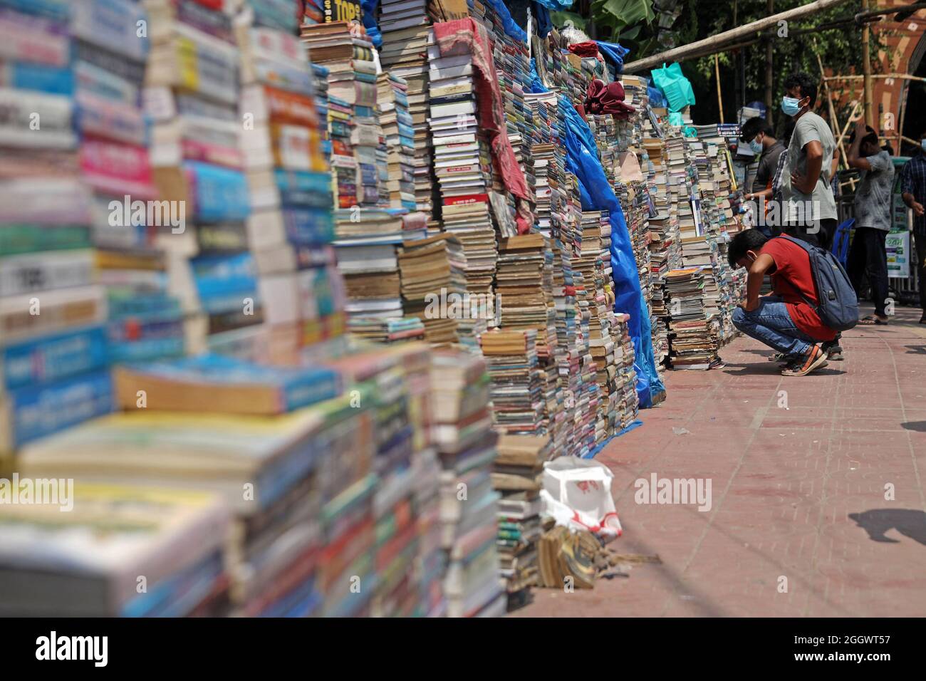 Dhaka, Bangladesch. September 2021. Ein Mann sieht aus, wie viele Bücher aufgestapelt wurden, die aufgrund der Schließung von Buchhandlungen aufgrund mangelnder Verkäufe aufgrund der Covid-19-Situation zu sehr niedrigen Preisen auf dem externen Markt versteigert wurden. Die alten Buchhandlungen in der Hauptstadt Newmarket haben aufgrund der Schließung von Bildungseinrichtungen aufgrund der Prävalenz von Covid-19 lange Zeit Verluste erlitten. Am 3. September 2021 in Dhaka, Bangladesch. Kredit: Eyepix Gruppe/Alamy Live Nachrichten Gutschrift: Eyepix Gruppe/Alamy Live Nachrichten Stockfoto