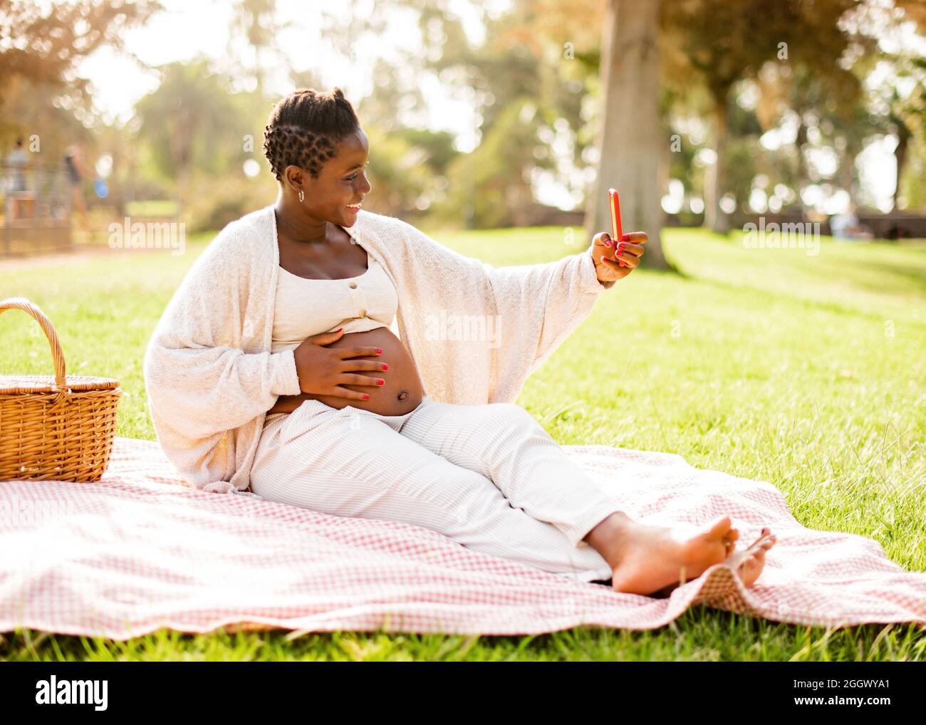 Schwanger afroamerikanische Frau nimmt Selfie im Park Stockfoto