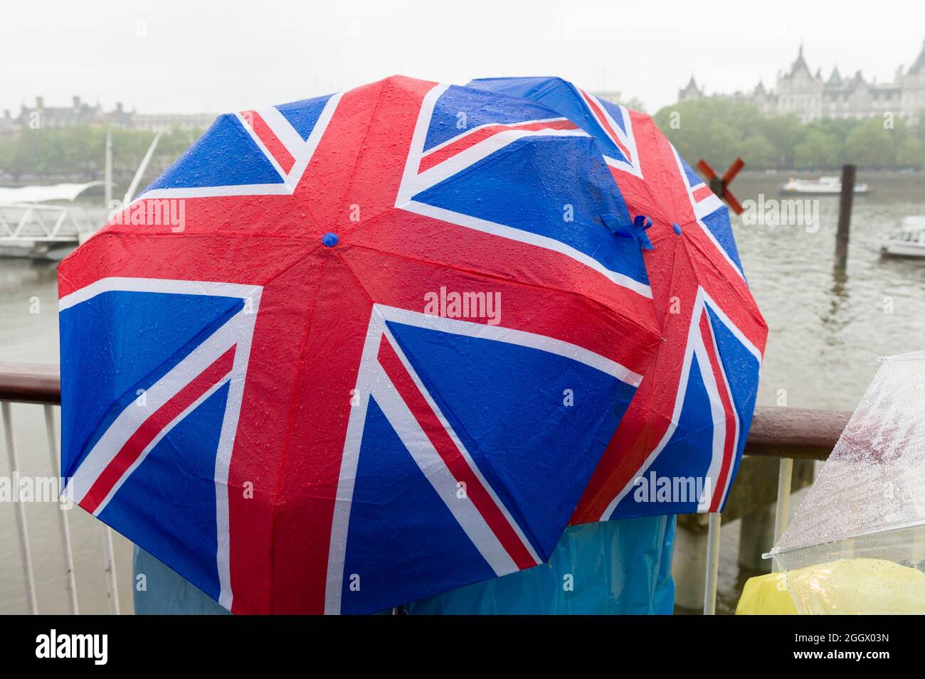 Zuschauer warten unter den Regenschirmen von Union Jack im Regen auf den Thames Diamond Jubilee Pageant, der am Londoner South Bank vorbeikommt. Der Pageant bestand aus Hunderten von Booten, die von der Battersea Bridge zur Tower Bridge segelten, um die 60 Jahre auf dem Thron von Königin Elizabeth II zu feiern. Millionen von Menschen säumten die Ufer der Themse, um das Spektakel zu beobachten. South Bank, London, Großbritannien. 3 Juni 2012 Stockfoto