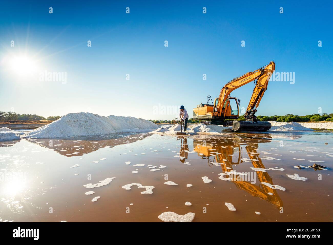 20. August 2021 - Faro, Portugal: Meersalzernte mit einem gelben Bagger bei natürlichen salinen Stockfoto