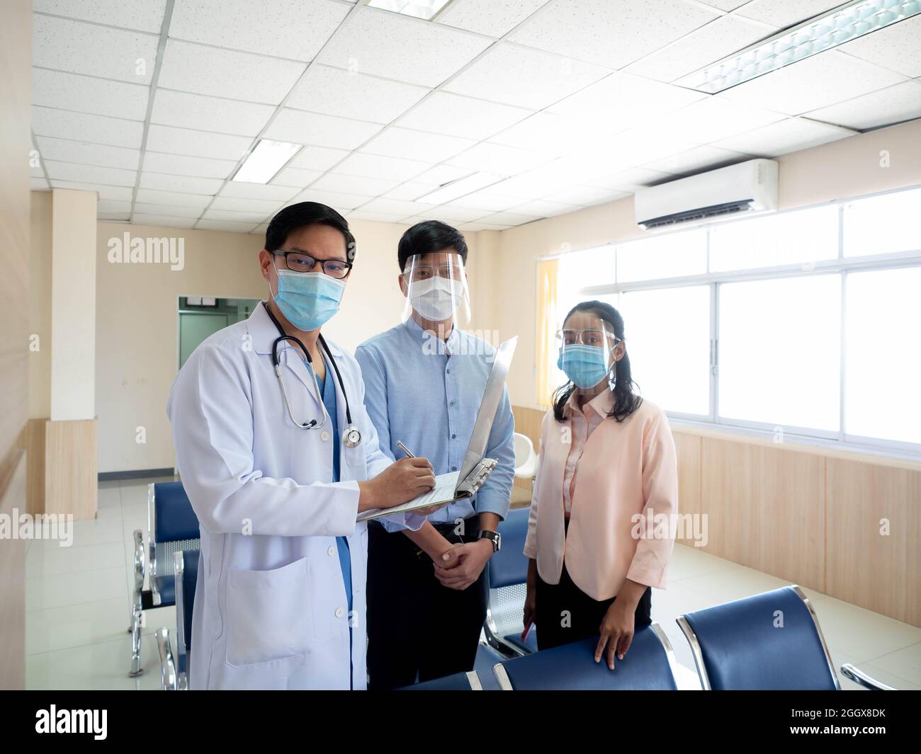 Krankenhaus Klinik oder Labor Arzt Wissenschaftler männlich Maske fragen Blick Kamera Bericht Patienten Behandlung Familie Mann weiblich Gesundheitsversorgung medizinische prot Stockfoto