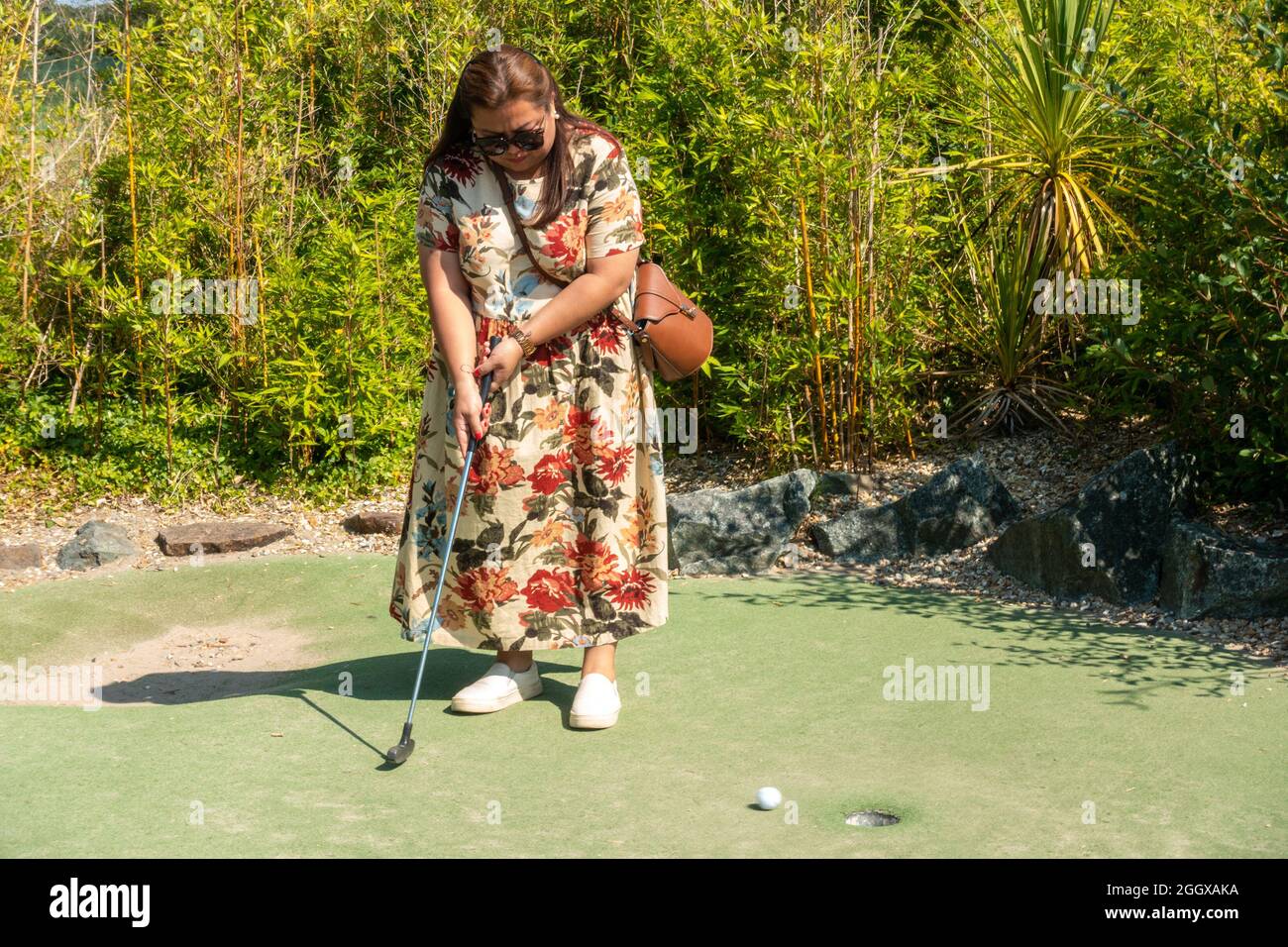 Eine Frau, die an einem sonnigen Tag verrücktes Golf spielt. Stockfoto
