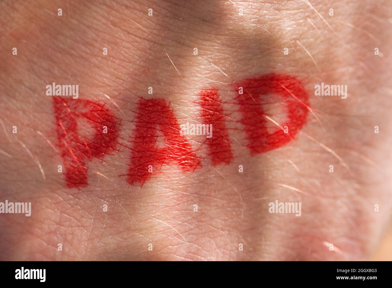 Roter Tintenstempel mit dem Wort, das auf dem Handrücken bezahlt wird Stockfoto
