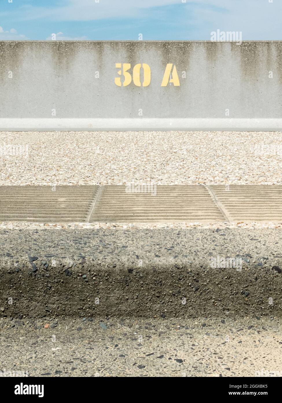 Gestrichene gelbe Farbe Nummer 30A auf einer betonierten Meereswand Stockfoto