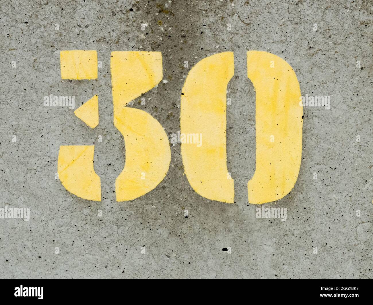 Gestrichelte gelbe Farbe Nummer 30 auf einer betonierten Meeresmauer Stockfoto