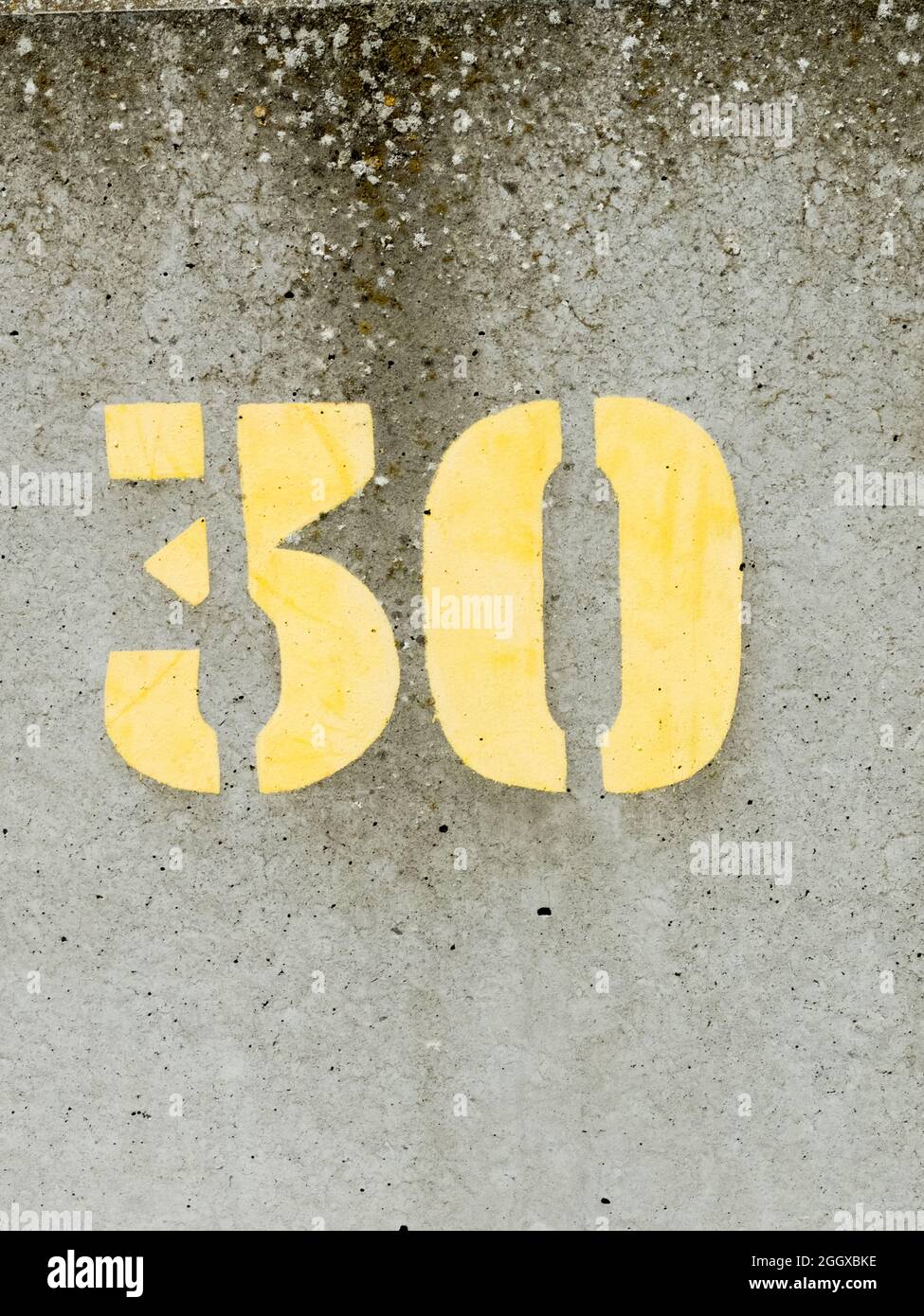 Gestrichelte gelbe Farbe Nummer 30 auf einer betonierten Meeresmauer Stockfoto