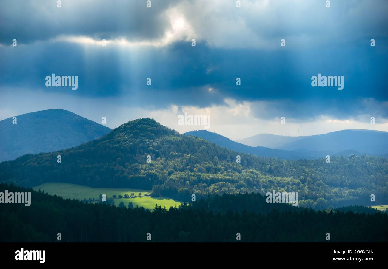 Malerische Aussicht auf den Berg Sokol bei Sonnenschein unter schweren dunklen Sturmwolken, wie vom Berg „Popova skala“ in der Tschechischen republik aus gesehen Stockfoto