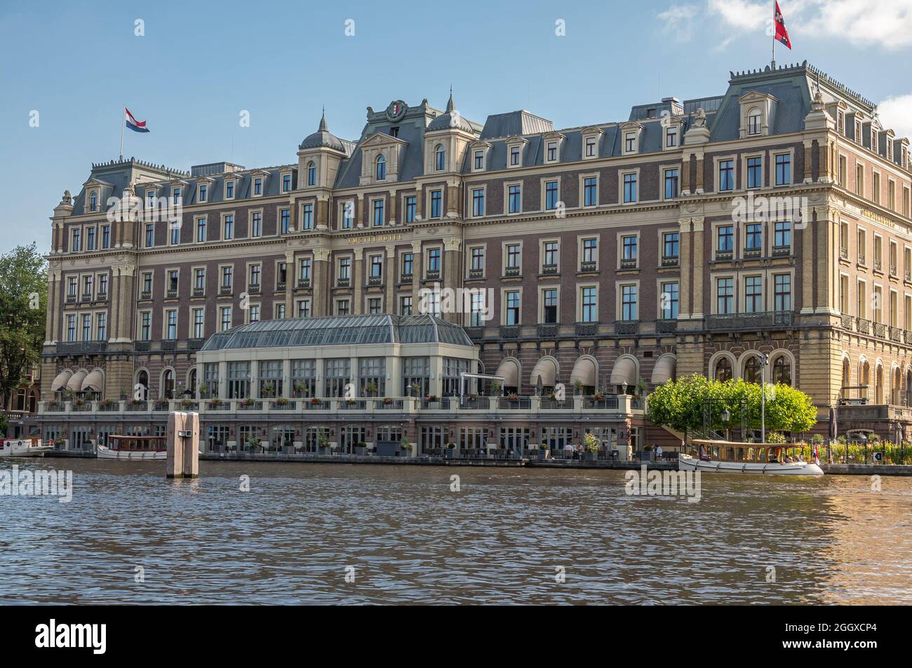 Amsterdam, Niederlande - 15. August 2021: Englische Schlossarchitektur des riesigen Intercontinental Amstel Hotels am Fluss Amstel unter blauem Wolkenstein Stockfoto