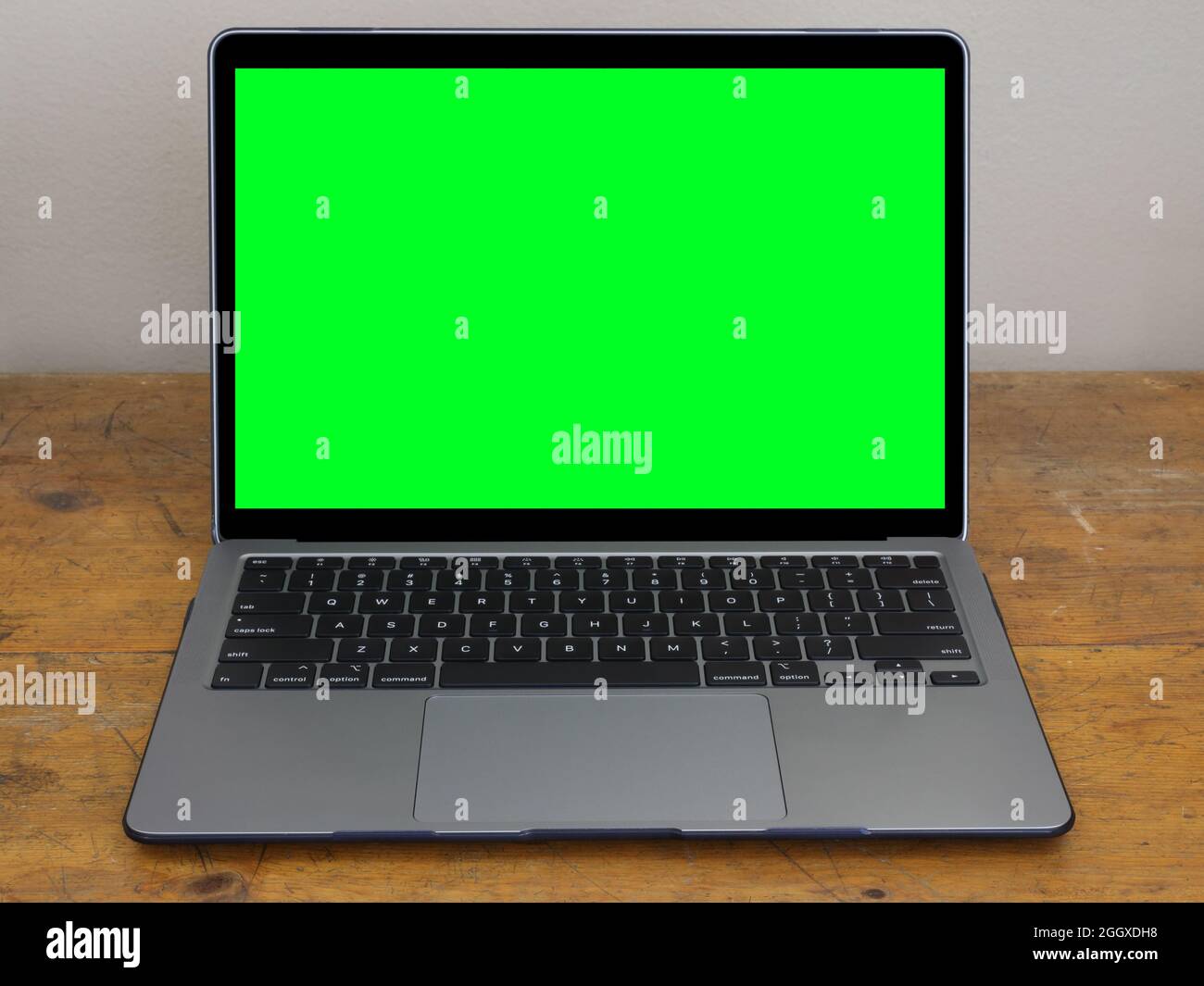 Ein moderner Laptop-Computer wird isoliert auf einem alten Büroschreibtisch aus Holz mit einem grünen Bildschirm auf dem Monitor angezeigt, um Ihre eigenen Grafiken hinzuzufügen. Stockfoto