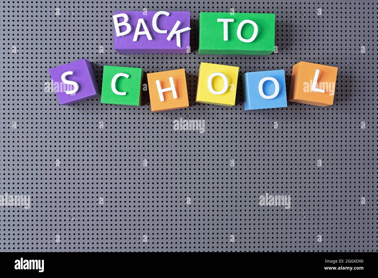 Bunte Würfel mit der Aufschrift 'Back to School' auf grauem Grund. Schulkonzept. Stockfoto