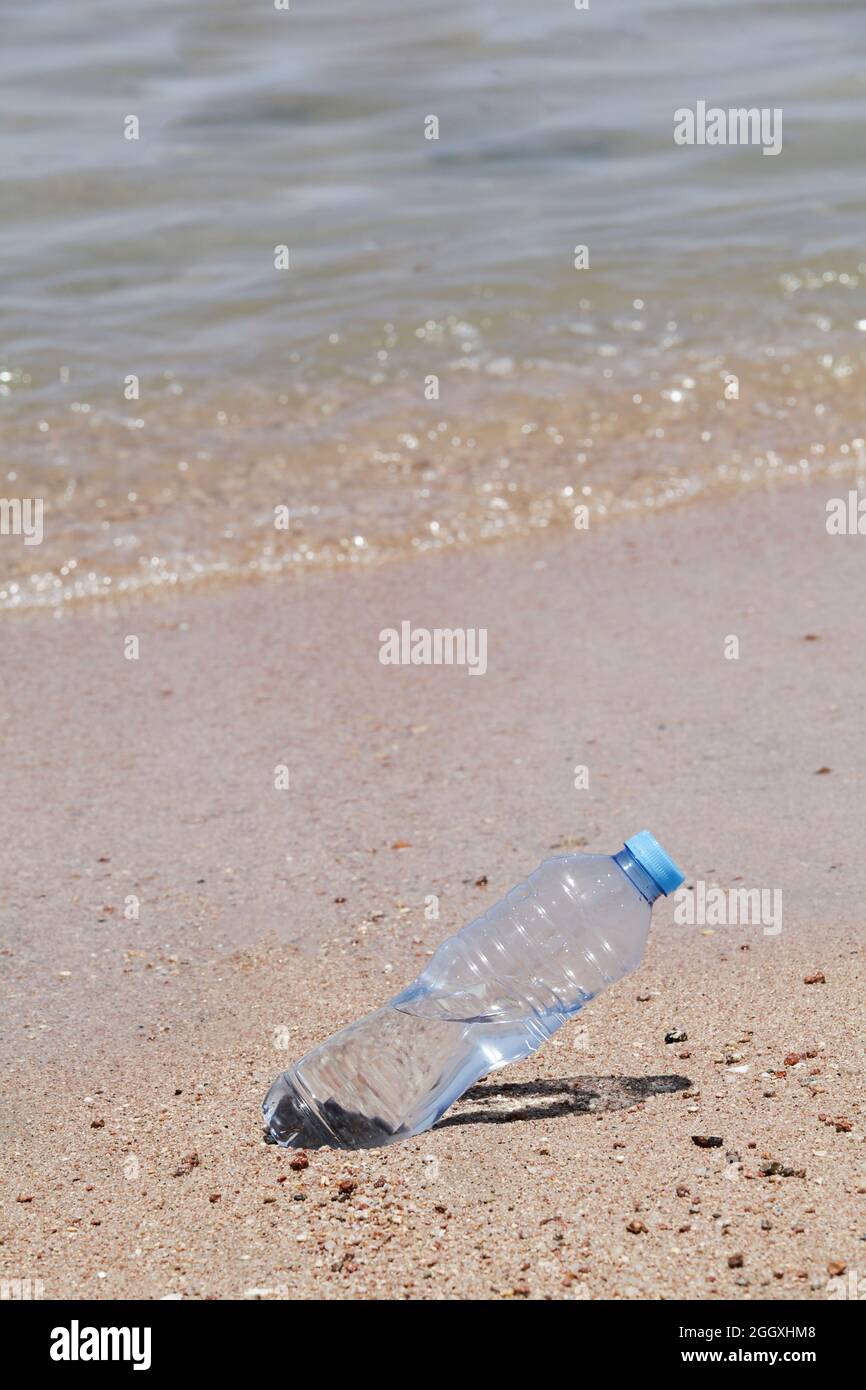 Konzept der Umweltverschmutzung. Plastikflasche am Strand in der Nähe des Meeres. Kopierraum. Weltweite Krise der Plastikverschmutzung. Stockfoto