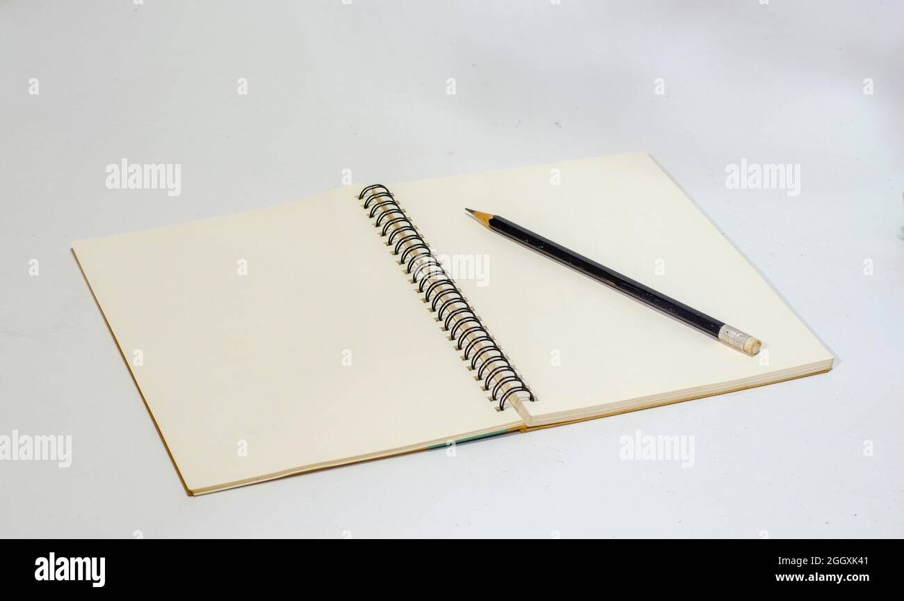 Nahaufnahme eines leeren Spiralbindungsnotizbuchs mit Bleistift auf einem weißen Tisch Stockfoto