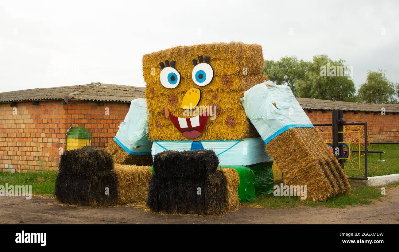 Eine Puppe aus Strohballen schmückt die traditionelle Feier des Endes der Weizenernte in Weißrussland. Inspiriert von einem modernen Thema wie SpongeBob. Stockfoto