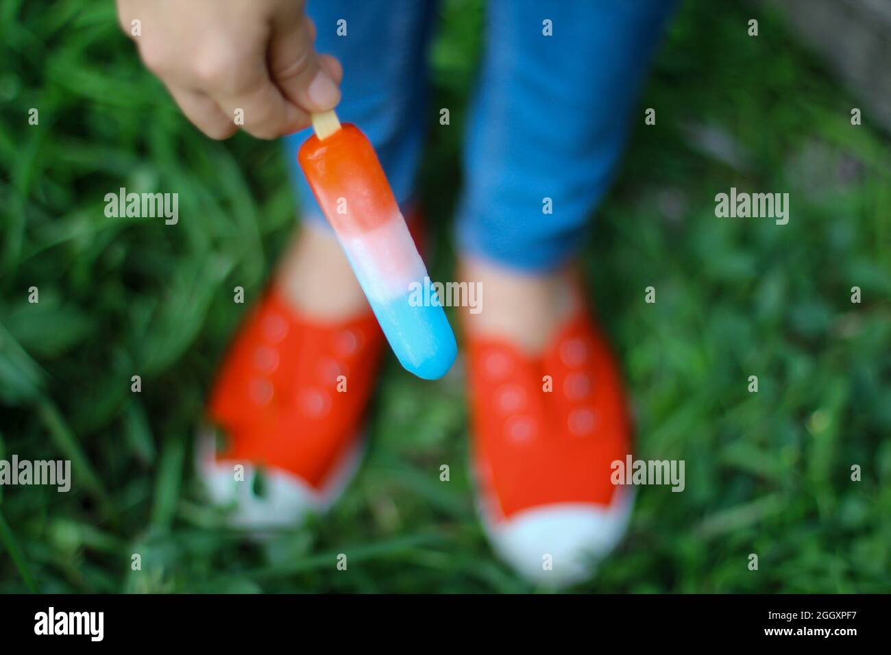 Person, die am 4. juli einen Rocket Popsicle, rot-weiß und blau gefrorenen Popsicle in der Hand hat. Stockfoto