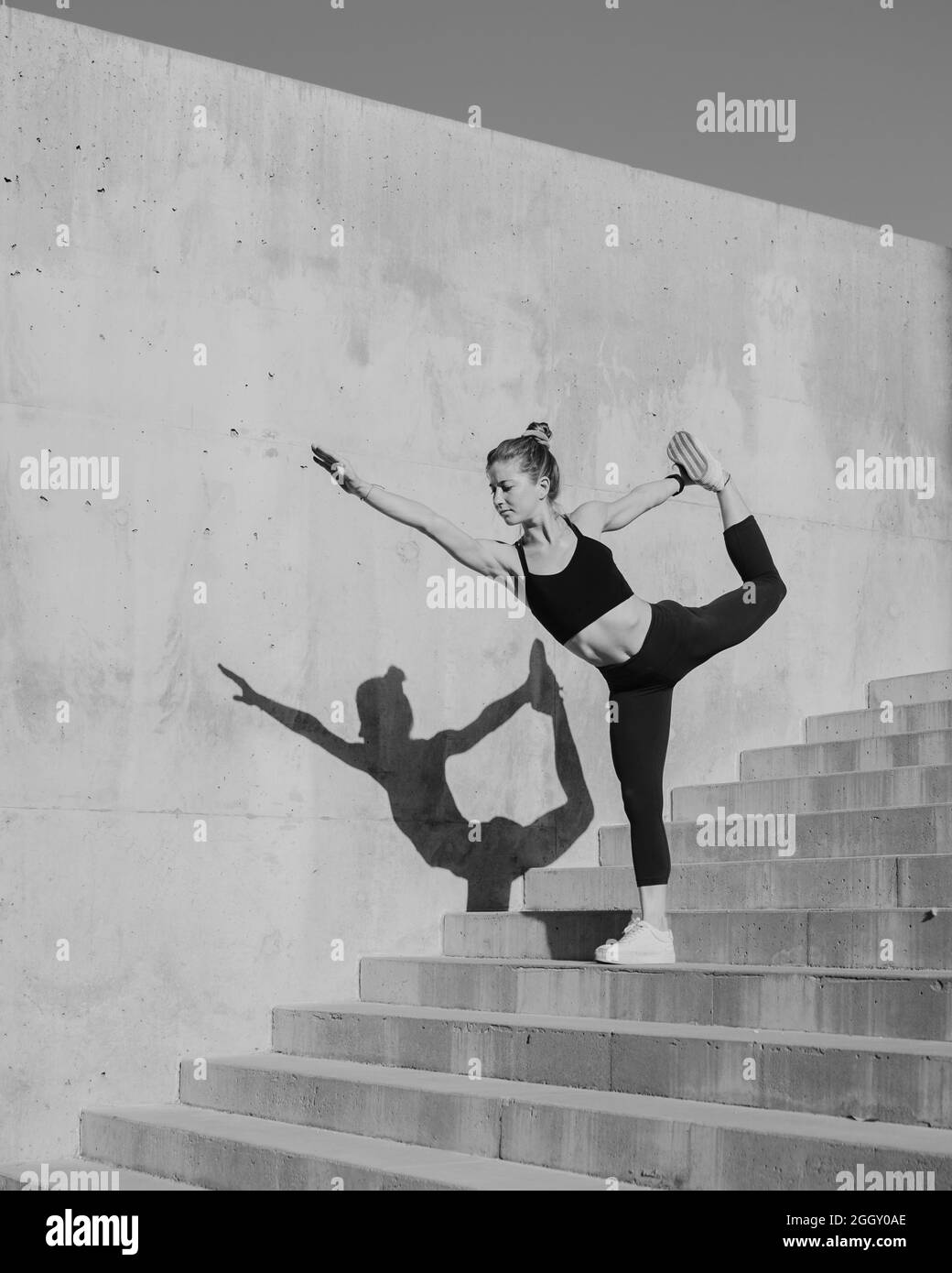 Schwarz-Weiß-Bild von Fit Young Woman doing Yoga Dancer Pose in Urban, Modern Environment Stockfoto