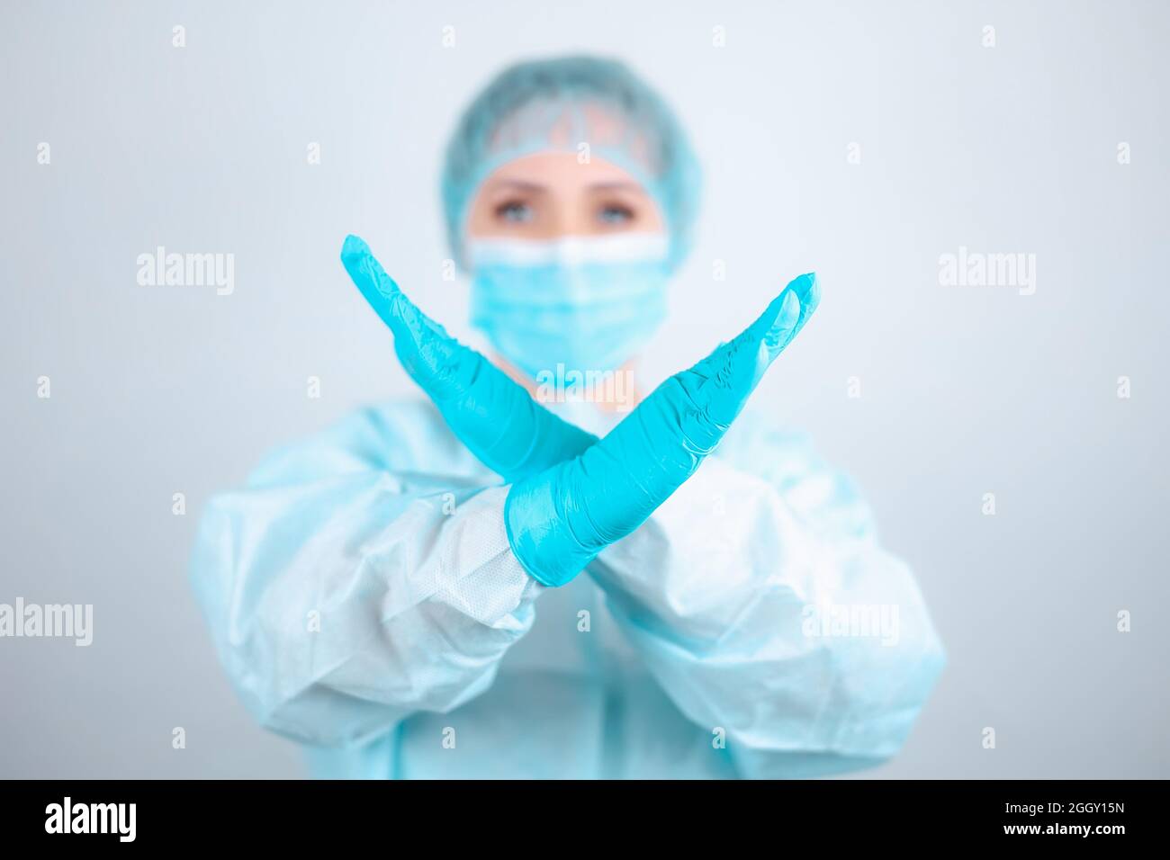 Eine Krankenschwester in einem medizinischen Gewand, einer Maske und Schutzhandschuhen steht aufrecht mit gekreuzten Armen vor ihr Stockfoto